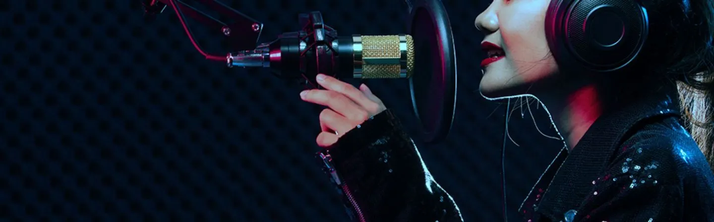 A singer in headphones recording at a studio microphone